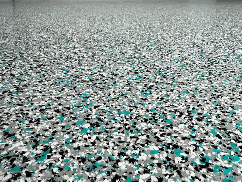 Close up of teal, black and grey flake epoxy floor coating texture